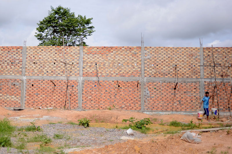 A construction worker walks past a wall built earlier this year around the site where a new prison will be constructed in Oddar Meanchey province. (Lauren Crothers/The Cambodia Daily)