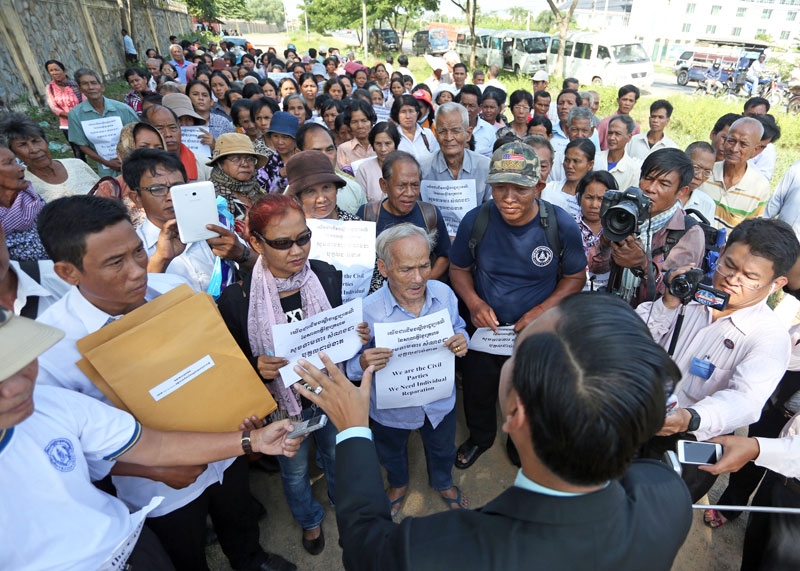 Khmer Rouge tribunal spokesman Neth Pheaktra speaks with victims of the Khmer Rouge who demonstrated outside the court on Friday to demand individual monetary reparations as civil parties in Case 002. (Siv Channa/The Cambodia Daily)