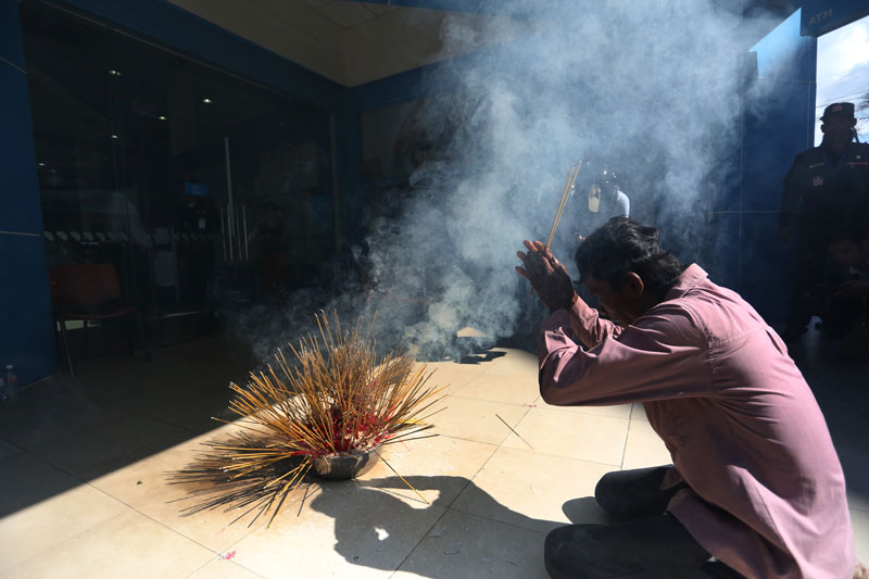 A man prays in front of the Phnom Penh headquarters of ANZ Royal Bank on Tuesday to lay a curse on the company. (Siv Channa/The Cambodia Daily)