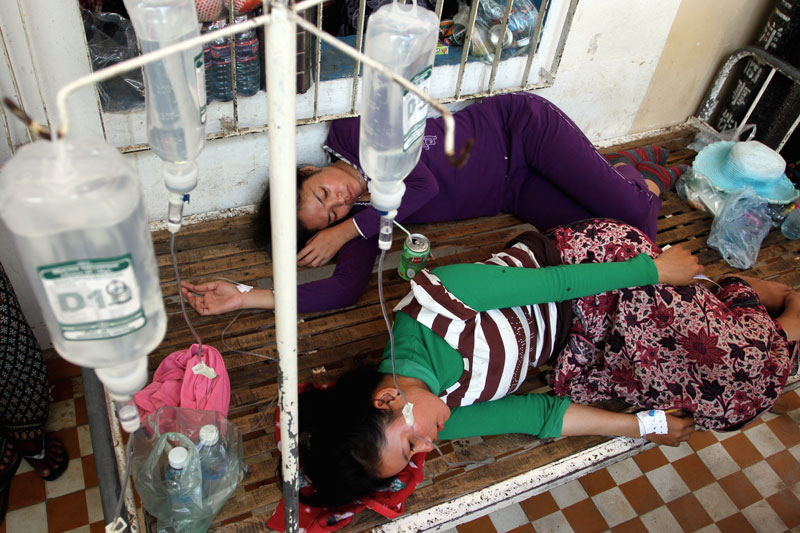 Two garment workers who were injured Tuesday when a floor collapsed at the Nishiku Enterprise factory in Takeo province lie outside Bati District Referral Hospital. (Siv Channa/The Cambodia Daily)