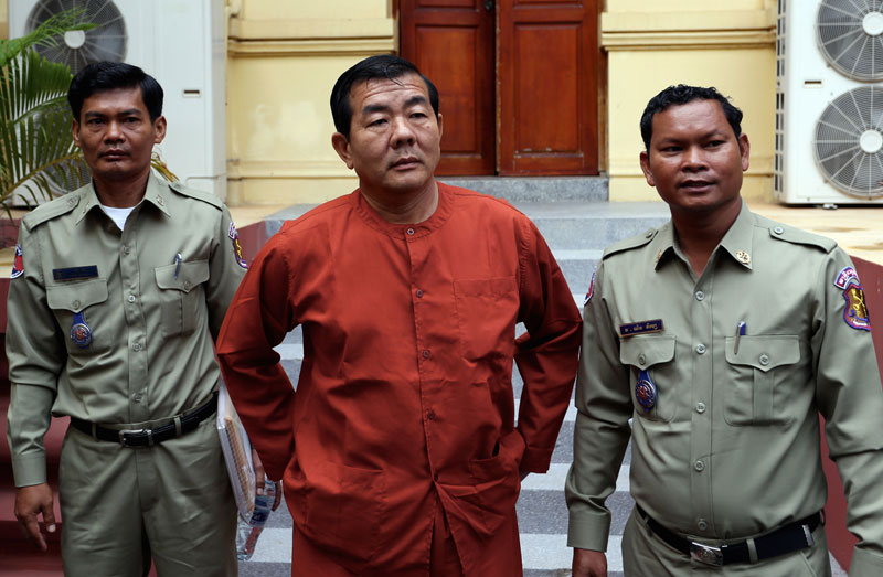 Disgraced former Phnom Penh police chief Heng Pov, center, stands outside the Supreme Court on Tuesday on the first day of a three-day hearing re-examining a trio of convictions against him handed down by the Phnom Penh Municipal Court over the past decade. (Siv Channa)