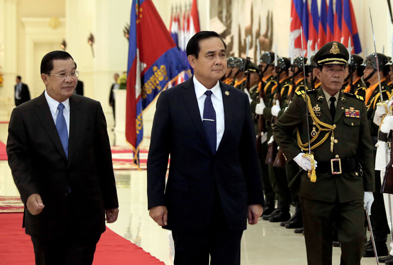 Prime Minister Hun Sen, left, and his Thai counterpart, General Prayuth Chan-ocha, walk past an honor guard prior to bilateral talks at the Peace Palace in Phnom Penh on Thursday. (Siv Channa/The Cambodia Daily)