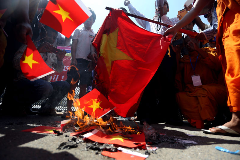 Protesters burn a Vietnamese flag, along with a number of paper replicas of the flag, outside the Vietnamese Embassy in Phnom Penh on Saturday. (Siv Channa/The Cambodia Daily)