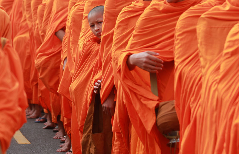 A young monk peers out from behind a line of fellow monks at a procession outside the Royal Palace on the second anniversary of the passing of late King Father Norodom Sihanouk on Wednesday. (Siv Channa/The Cambodia Daily)