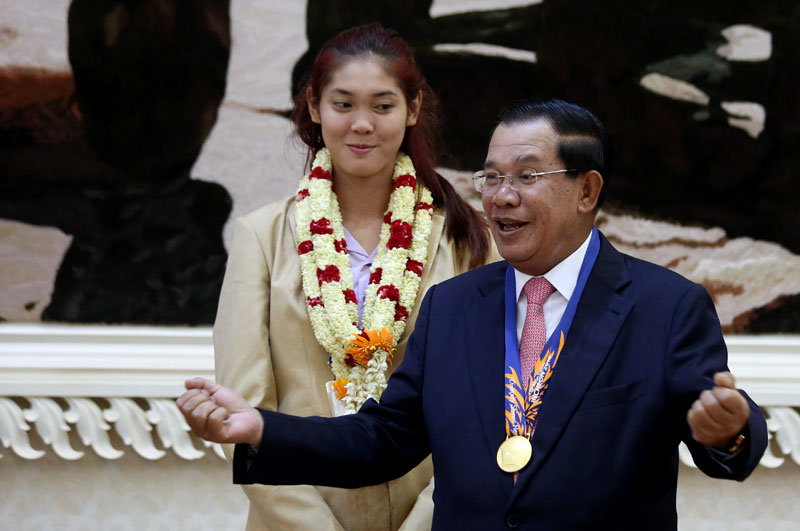 Prime Minister Hun Sen tries on the gold medal won by Asian Games taekwondo champion Sorn Seavmey, left, at the Peace Palace in Phnom Penh on Sunday night. (Siv Channa/The Cambodia Daily)