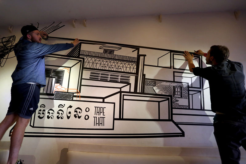 German artists Nicolas Lawin, left, and Stefan Busch work Friday on a piece of tape art depicting a Phnom Penh streetscape. (Siv Channa/The Cambodia Daily)