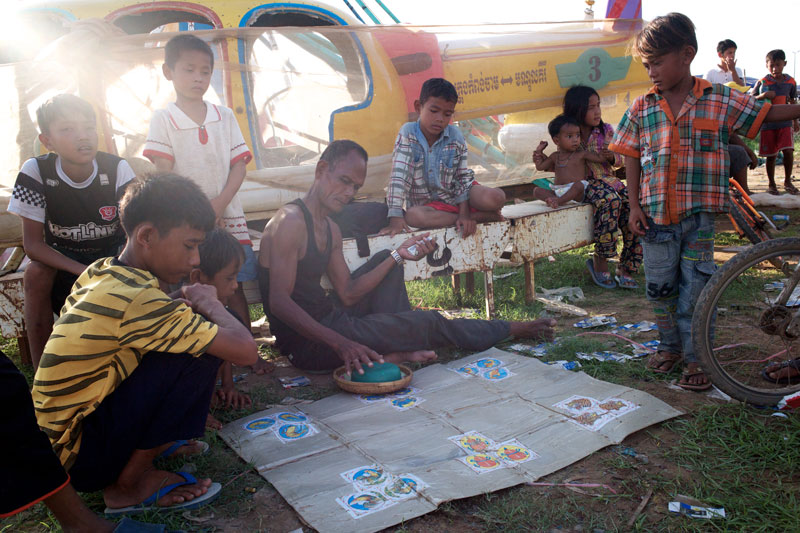 Children watch on as a carny plays a traditional card game. (Ben Woods/The Cambodia Daily)