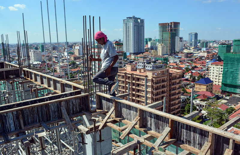 Construction worker Phal Roeun, 32, makes his way along a wooden frame atop a condominium construction site on Street 352 in Phnom Penh's Chamkar Mon district. (Alex Consiglio/The Cambodia Daily)
