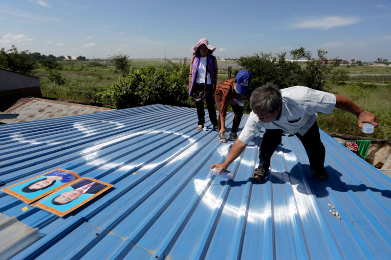 Residents of the Thma Koul neighborhood, under threat of eviction due a planned expansion of Phnom Penh International Airport, spray-paint 'SOS' on a rooftop Thursday in the hope of catching the eye of Prime Minister Hun Sen, who flew back from the 25th Asean Summit in Burma Thursday evening. (Siv Channa/The Cambodia Daily)