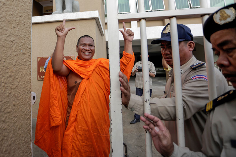 Activist monk Luon Sovath gestures to supporters as he enters the Phnom Penh Municipal Court on Tuesday morning. (Siv Channa/The Cambodia Daily)