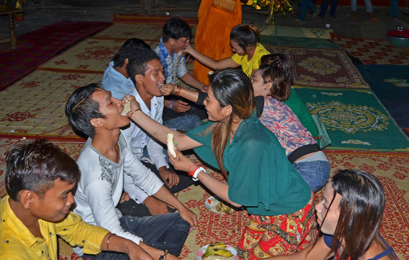 Young people feed each other fruit and pounded rice during the Ak Ambok ceremony at Treng Trayoeng pagoda in Kompong Speu province's Phnom Sruoch district on Thursday night. (George Wright/The Cambodia Daily)