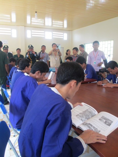 Inmates pose with books for photographers at Kandal provincial prison's new library this week. (Denise Hruby/The Cambodia Daily)