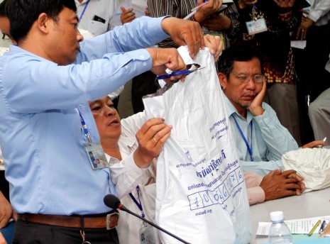 An employee from the National Election Committee in Phnom Penh on Sunday opens a sealed package in which original documents from polling stations were secured on election day. Many of the packages revealed to the public were improperly sealed, raising fears they had been tampered with. (Siv Channa)