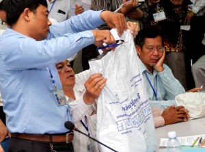 An employee from the National Election Committee in Phnom Penh opens a sealed package in which original documents from polling stations were secured on election day in 2013. (Siv Channa)