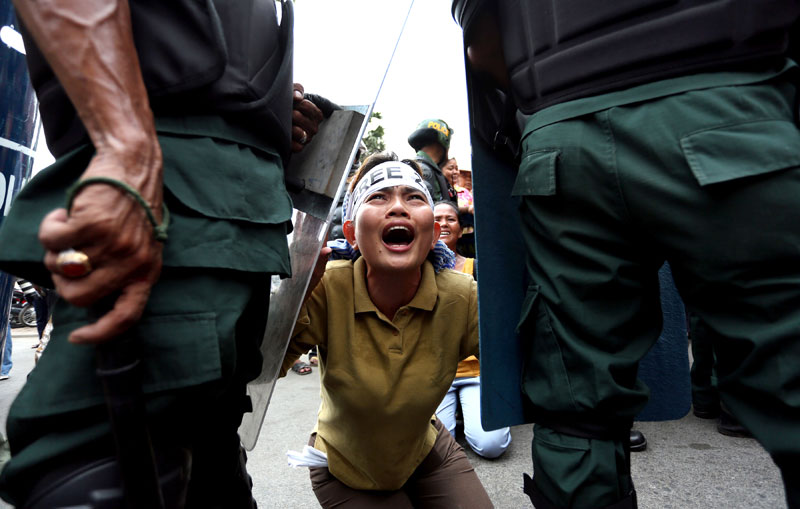 Boeng Kak activist Yorm Bopha is blocked by police as she screams in support of detained labor activists Vorn Pao and Sokun Sombath Piseth outside their bail hearing in Phnom Penh on Friday. (Siv Channa)