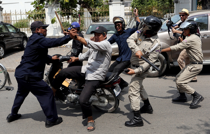 Daun Penh district security guards attack a man on his motorcycle on Street 51 in Phnom Penh shortly after opposition leaders Sam Rainsy and Kem Sokha departed from the area during their International Labor Day march through the city on Thursday. (Siv Channa)