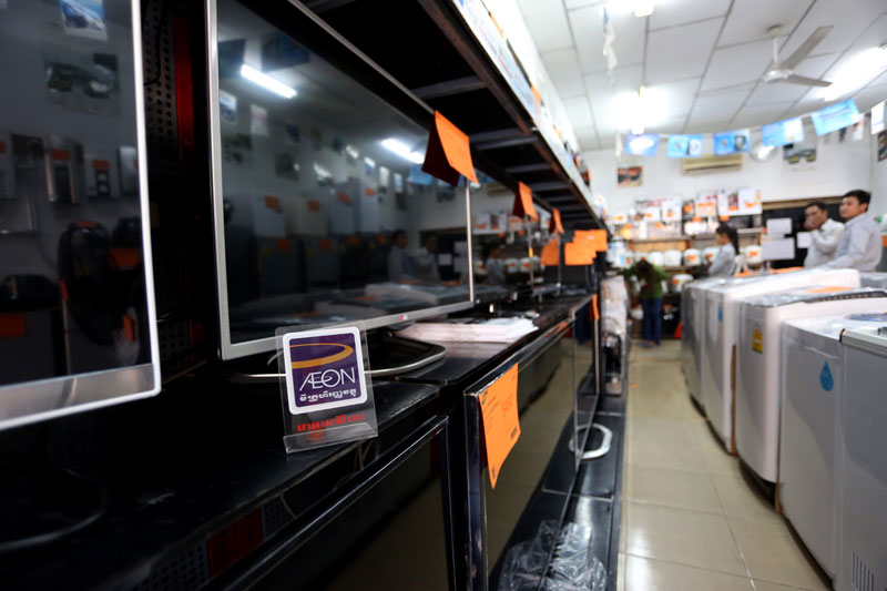 An Aeon Microfinance sign stands among a row of televisions in a Sony store in Phnom Penh. (Siv Channa)