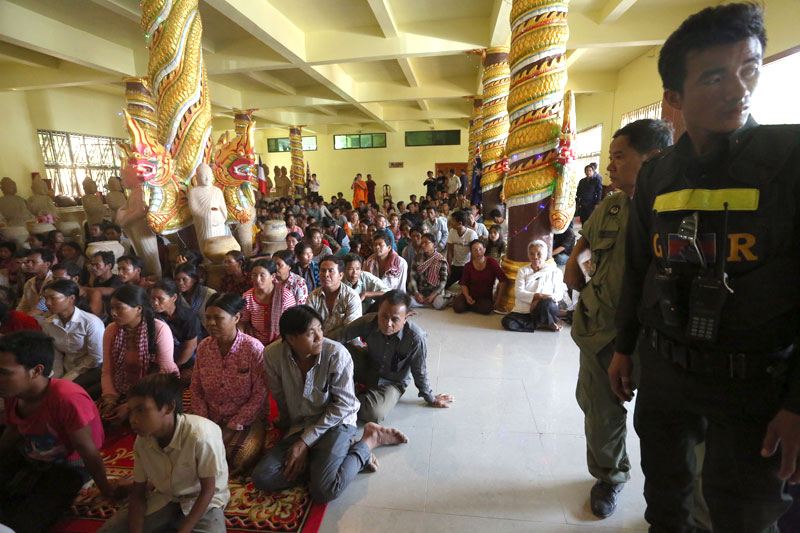 Displaced villagers locked in a land dispute with a Vietnamese rubber firm in Kratie province sit at the Samakki Raingsey pagoda in Phnom Penh on Thursday as police and military police look on. (Siv Channa)