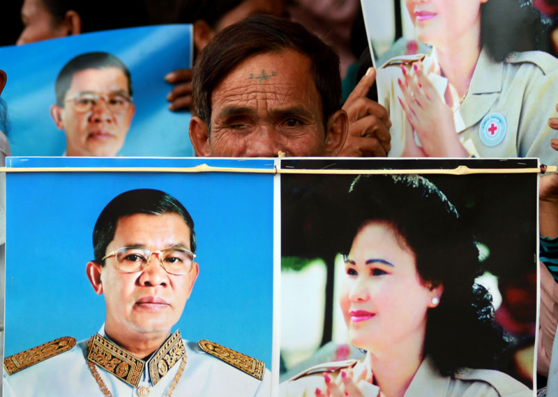 A former Khmer Rouge soldier from Banteay Meanchey province holds photos of Prime Minister Hun Sen and his wife Bun Rany at Wat Botum park on Friday. A group of former soldiers are asking the prime minister to intervene in their land dispite. (Siv Channa/The Cambodia Daily)