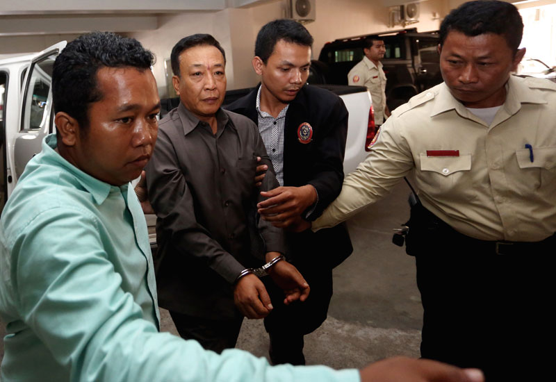Anti-Corruption Unit officials escort Meanchey district police chief Hy Narin into the Phnom Penh Municipal Court for questioning on Thursday. (Siv Channa/The Cambodia Daily)