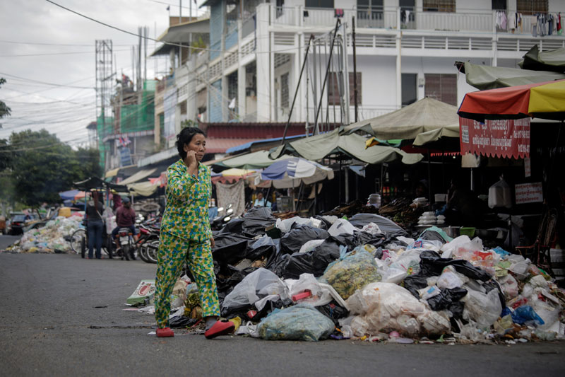 A woman walks past a large pile of trash outside Phsar Kabko in Phnom Penh's Chamkar Mon district Tuesday. (Siv Channa/The Cambodia Daily )