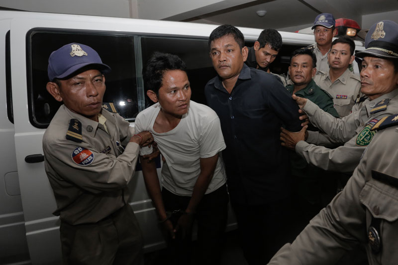 Police escort murder suspects Ly Sao, 28, left, and Sieng Veasna, 44, out of a van at the Phnom Penh Municipal Court Thursday. Mr Veasna is the alleged gunman in the fatal shooting of businessman Ung Meng Chue last month. Mr Sao is the suspected getaway driver. (Siv Channa/The Cambodia Daily)
