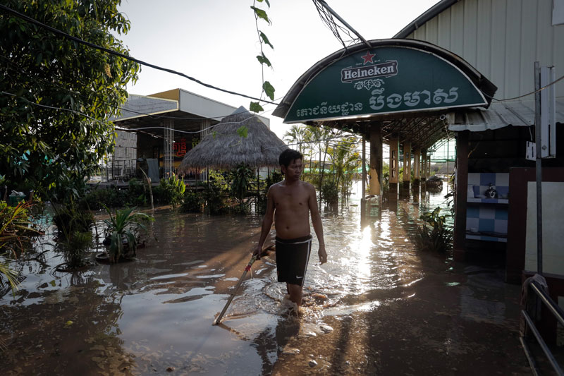 District Tells Development Firm to Compensate Flooded Eateries 1 An employee of the Boeung Meas restaurant in Phnom Penh wades through water that flooded the establishment Wednesday. (Siv Channa/The Cambodia Daily)