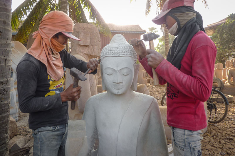 Two young stonemasons begin painstaking detail work on a statue of the Buddha. (Anthony Jensen/The Cambodia Daily)