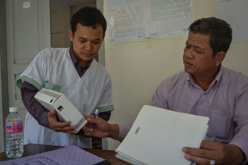 By Beng Sor, director of the Roka commune health center in Battambang province, left, and Im Chetra, director of the Sangke operational district health department, examine an HIV test kit at the commune health center on December 17. (Alex Consiglio/The Cambodia Daily)