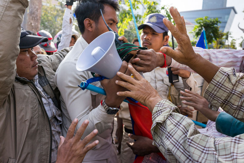 A municipal security guard grabs a bullhorn away from protesters in front of Phnom Penh City Hall on Monday. (John Vink)