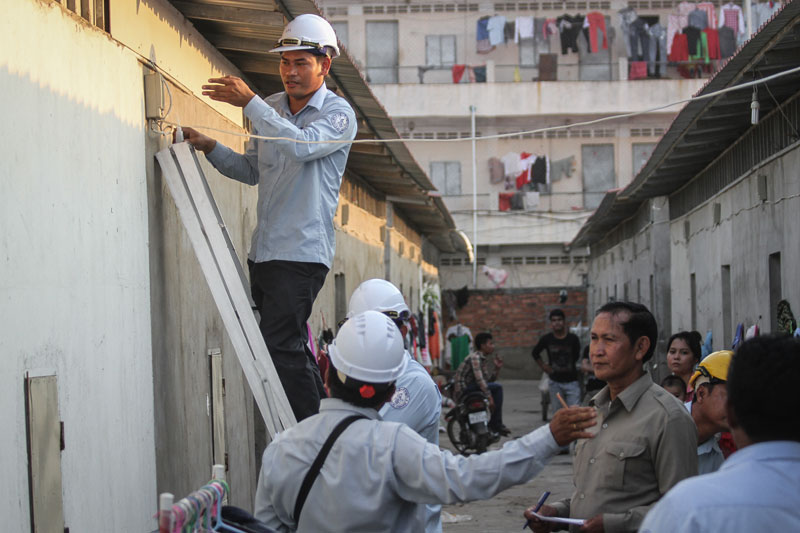 Electricite du Cambodge employees inspect the electrical system outside an apartment building in Phnom Penh's Russei Keo district Thursday. (Siv Channa/The Cambodia Daily)