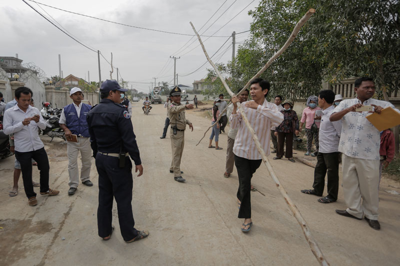 A man carries wooden poles to the scene of a land dispute in Phnom Penh on Tuesday, hoping to demarcate his claim. About 50 people who say they were awarded part of a one-hectare plot in Sen Sok district scuffled briefly with the family of a woman living on the land before police broke up the two sides. (Siv Channa/Cambodia Daily)