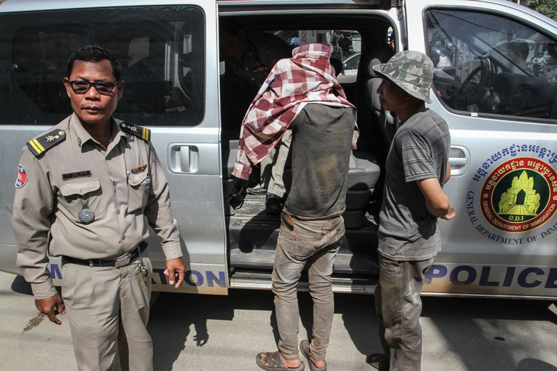 Two Vietnamese men are escorted into a police van. (Siv Channa/The Cambodia Daily)