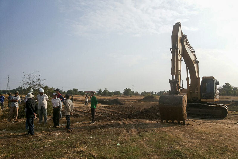 Villagers gather on Saturday near an excavator beginning to dig a 52-hectare reservoir that will engulf their rice fields in Banteay Meanchey province's Serei Saophoan City. (Adhoc)