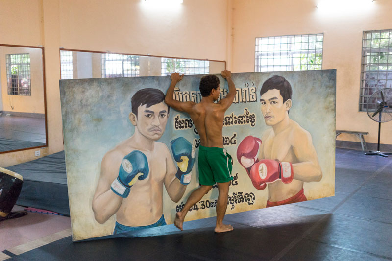 Dancer Nget Rady on Monday moves an old boxing-match poster that will be used as a prop for the dance. (John Vink)