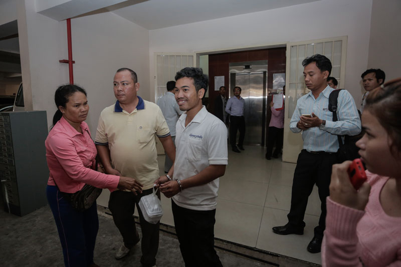 Union leader Seang Rithy, in handcuffs, who was arrested Tuesday for transporting bamboo poles to a strike outside a factory in Phnom Penh, is escorted by a plainclothes police officer after being questioned at the municipal court Wednesday. (Siv Channa/The Cambodia Daily)
