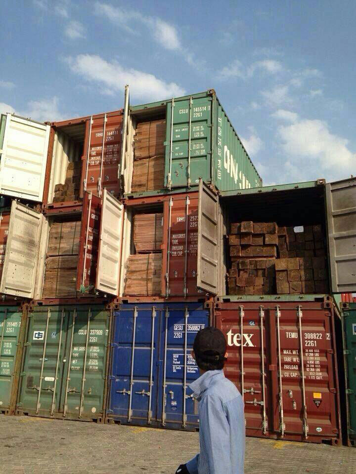 A man walks past shipping containers holding Siamese rosewood belonging to timber magnate Try Pheap at the international port in Sihanoukville in early 2014. (Global Witness)