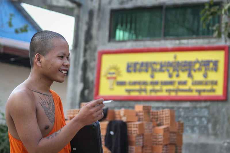 A monk smokes a cigarette at Samakki Raingsey pagoda in Phnom Penh on Monday. (Siv Channa/The Cambodia Daily)