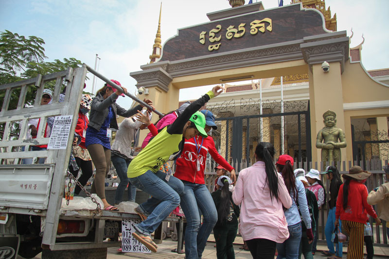 Protesting garment workers from the Smart Shirts factory in Phnom Penh leap off the back of a truck at the National Assembly last year. (Siv Channa/The Cambodia Daily)