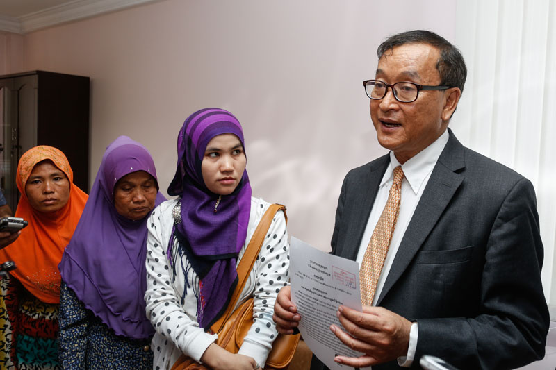 Cham Muslim women, along with a translator, look on as opposition leader Sam Rainsy speaks to the media about their daughters, who were trafficked to Malaysia, at the National Assembly on Monday. (Siv Channa/The Cambodia Daily)