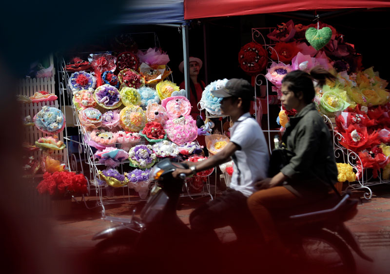A man and woman ride past a pop-up store selling bouquets for Valentine's Day on Street 51 in Phnom Penh's Daun Penh district on Friday. (Siv Channa/The Cambodia Daily)