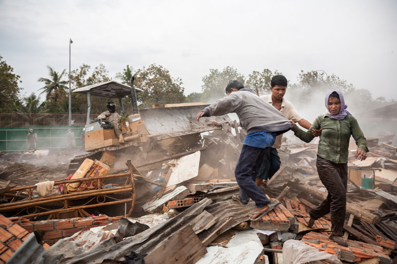 Residents flee a bulldozer as it moves rubble from homes destroyed during the forced eviction of Dey Krahorm residents in Phnom Penh in January 2009. (Nicolas Axelrod)