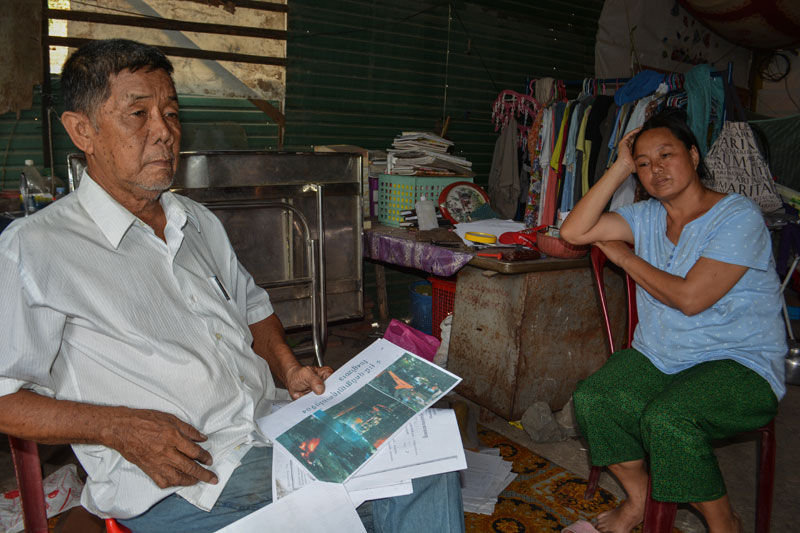 Court Orders Family off Khun Sear’s Land, Lawyer Says 1 Sitting inside their home in Phnom Penh's Tuol Kok district on Thursday, Ly Sreang Kheng and his wife Mok Siv Hong sort through images that they claim prove security guards employed by Khun Sear's company beat them. (Alex Consiglio/The Cambodia Daily)
