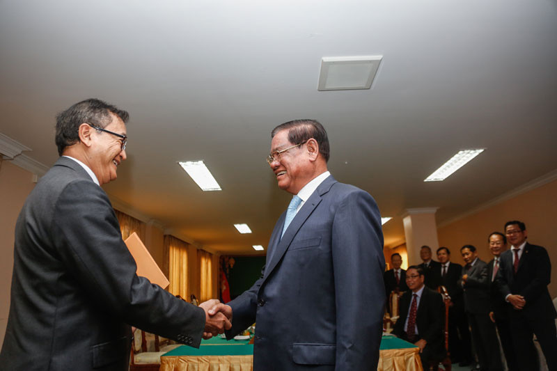 Opposition leader Sam Rainsy, left, and Interior Minister Sar Kheng shake hands before leading the CNRP and CPP in negotiations over amendments to the election law at the National Assembly on Saturday. (Siv Channa/The Cambodia Daily)