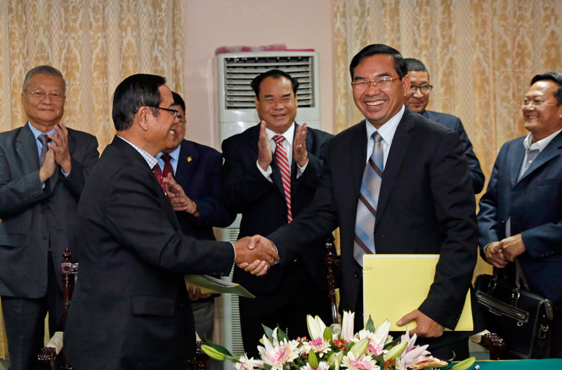 Deputy Prime Minister Bin Chhin, left, shakes hands with senior CNRP official Kuoy Bunroeun at the National Assembly on Friday during the signing ceremony of a new draft election law, which is expected to be voted on by lawmakers in the coming weeks. (Siv Channa/The Cambodia Daily)