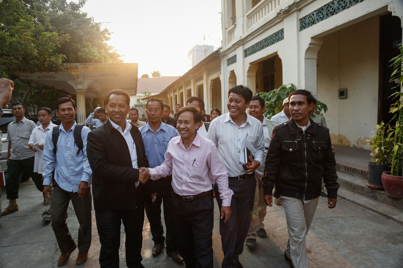 E Sophors, left, and Vorn Pao, who head rival tuk-tuk associations, shake hands following a meeting at the Daun Penh district office on Monday to settle a dispute over passengers in front of the Phnom Penh railway station earlier this month. (Siv Channa/The Cambodia Daily)