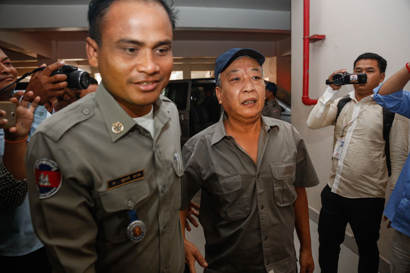 Disgraced former Meanchey district police chief Hy Narin is escorted up the stairs at the Phnom Penh Municipal Court on Wednesday. (Siv Channa/The Cambodia Daily)