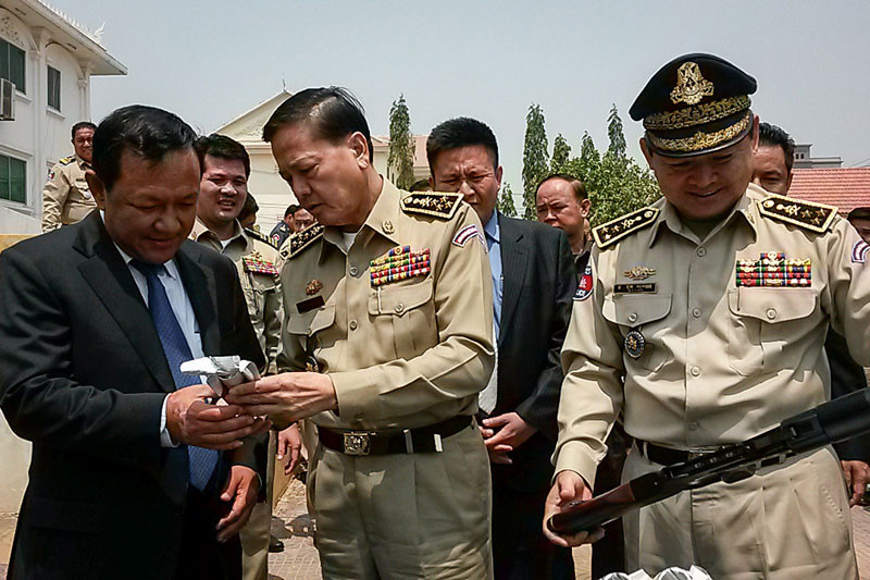 Phnom Penh governor Pa Socheatvong, left, National Police chief Neth Savoeun, center, and Phnom Penh Municipal Police chief Chuon Sovann inspect a smoke grenade and launcher at the annual municipal police meeting in Phnom Penh on Tuesday. (Mech Dara/The Cambodia Daily)