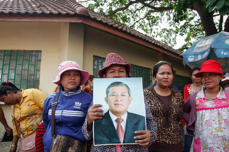 A worker from the Kui Xing garment factory holds up a photograph of Prime Minister Hun Sun during a protest outside the Phnom Penh Municipal Court on Tuesday. (Siv Channa/The Cambodia Daily)