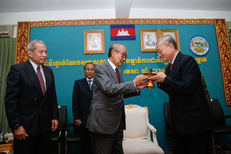 Royal Palace Minister Kong Sam Ol, center, officially hands over leadership of the National Election Committee to its new chairman, Sik Bunhok, at a ceremony at the Interior Ministry in Phnom Penh on Monday. (Siv Channa/The Cambodia Daily)